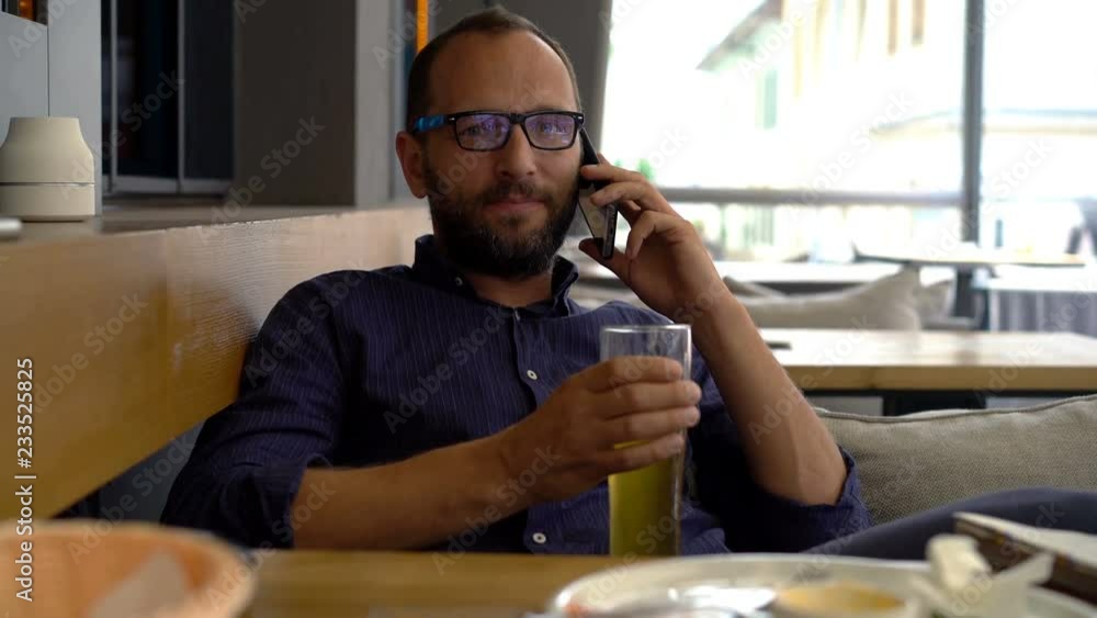Young man talking on cellphone and drinking beer in cafe Young man talking on cellphone and drinking beer in cafe