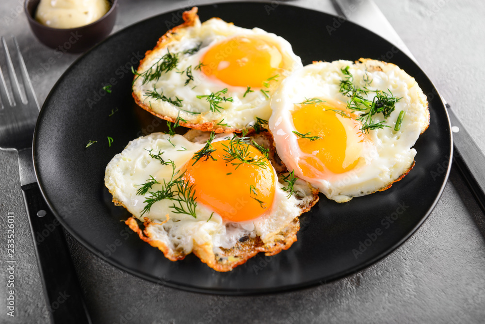 Plate with tasty fried eggs on grey table Plate with tasty fried eggs on grey table