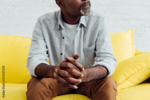 close up of african american mature man sitting on yellow sofa