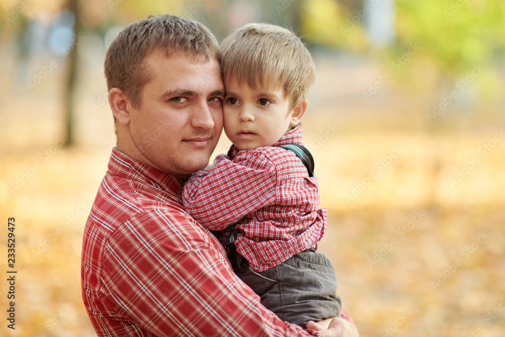 Father and son are playing and having fun in autumn city park. They posing, smiling, playing. Bright yellow trees. Father and son are playing and having fun in autumn city park. They posing, smiling, playing. Bright yellow trees.
