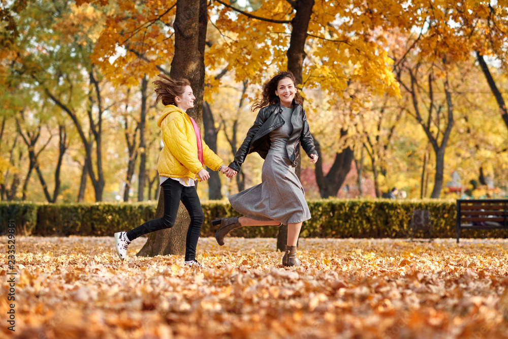 Two happy girls running in autumn city park. Two happy girls running in autumn city park.