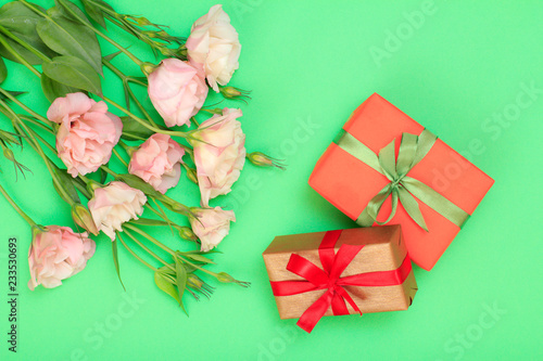 Pink flowers with leaves and gift boxes with ribbon on green background