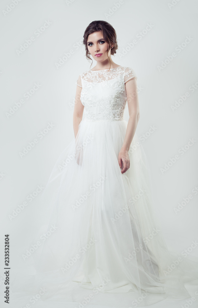 Attractive woman bride with makeup and bridal hairstyle posing on white background
