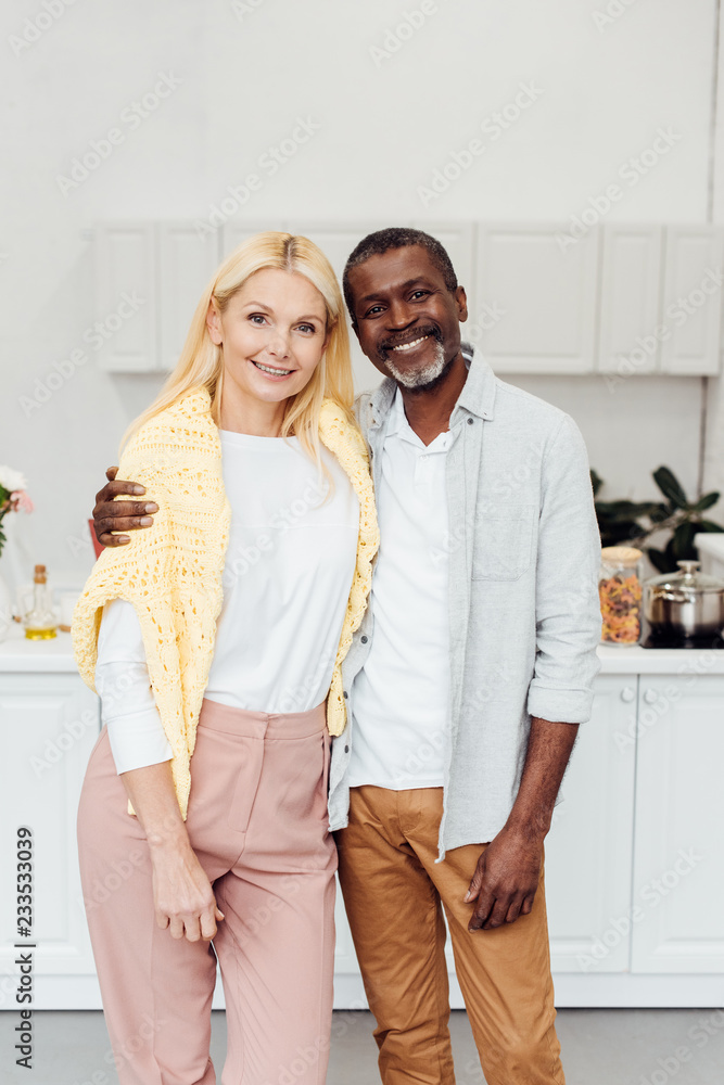 african american man embracing blonde mature woman at kitchen african american man embracing blonde mature woman at kitchen