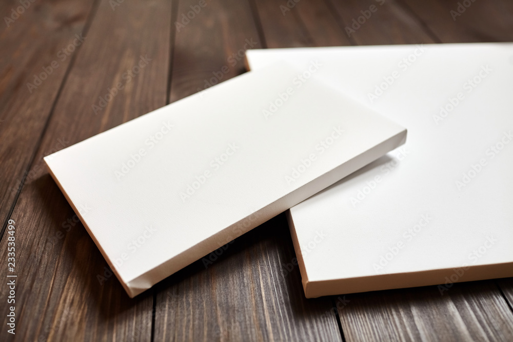Two white blank canvases on brown wooden background. Mockup Two white blank canvases on brown wooden background. Mockup