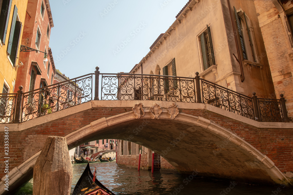View from a Venetian gondola of an ancient bridge on a canal in summer, Venice, Italy