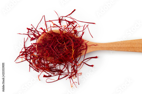 Saffron spice threads (strands) in wooden spoon isolated on white background