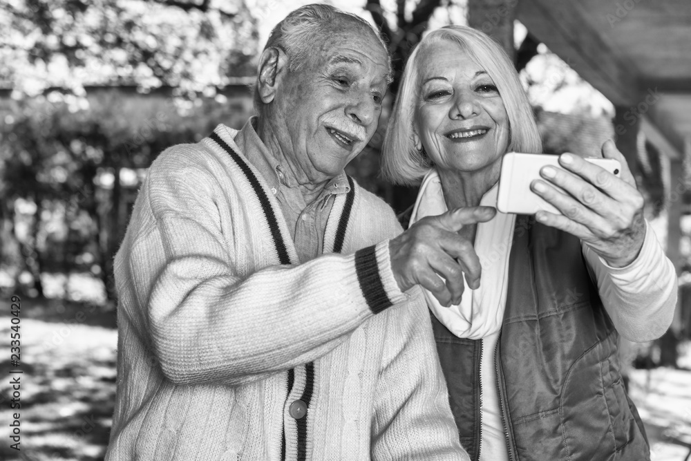 Obraz premium Elderly couple looking at the photos of their grandchildren on their cell phones