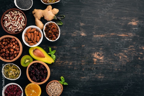 Various superfoods. Dried fruits, nuts, beans, fruits and vegetables. On a black wooden background. Top view. Free copy space. © Yaruniv-Studio