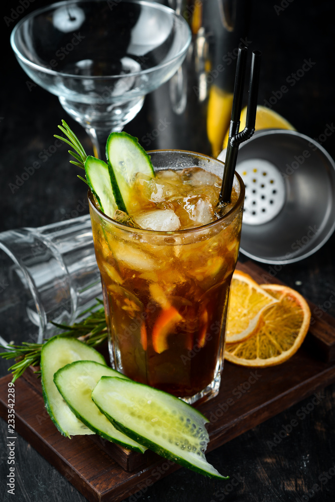 Tasty alcoholic cocktail. Cola, whiskey, cucumber and ice. On a wooden background. Top view. Tasty alcoholic cocktail. Cola, whiskey, cucumber and ice. On a wooden background. Top view.