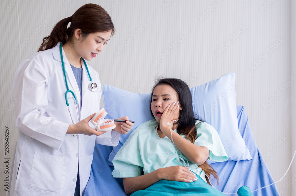 Woman dentist talking with her female patient explain with tooth model and preparing to treatment at dental center Woman dentist talking with her female patient explain with tooth model and preparing to treatment at dental center