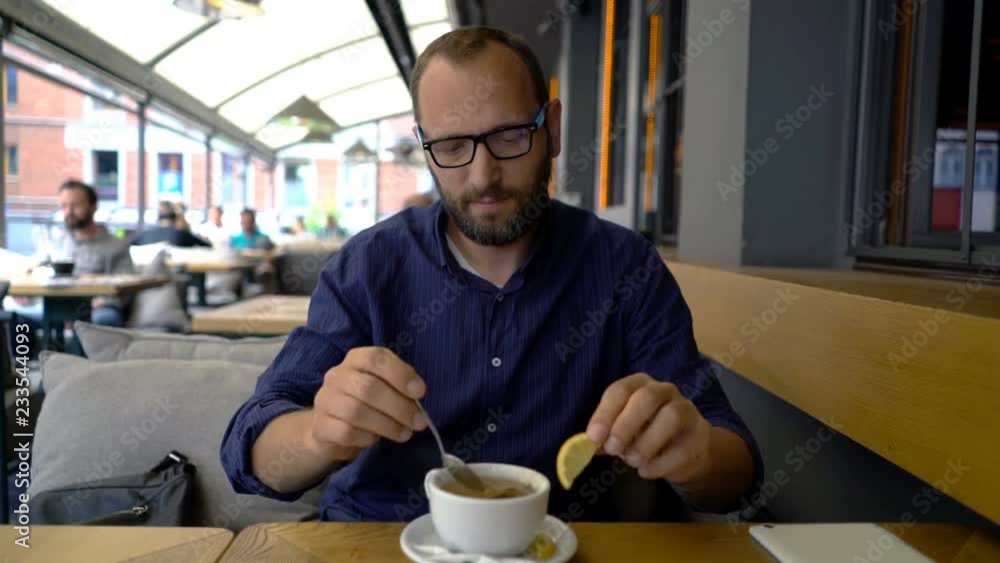 Man preparing and mixing tea sitting in cafe Man preparing and mixing tea sitting in cafe