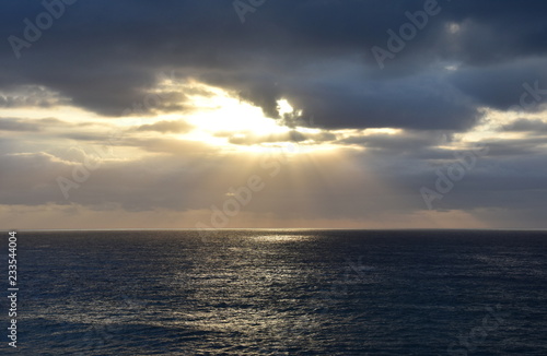 Natural sunrise sky landscape view. Dramatic sunrise cloudy sky with clouds lit by sunlight. Sunlight on horizon ocean on background seascape rays sunrise. Relax view waves sea on evening sand beach