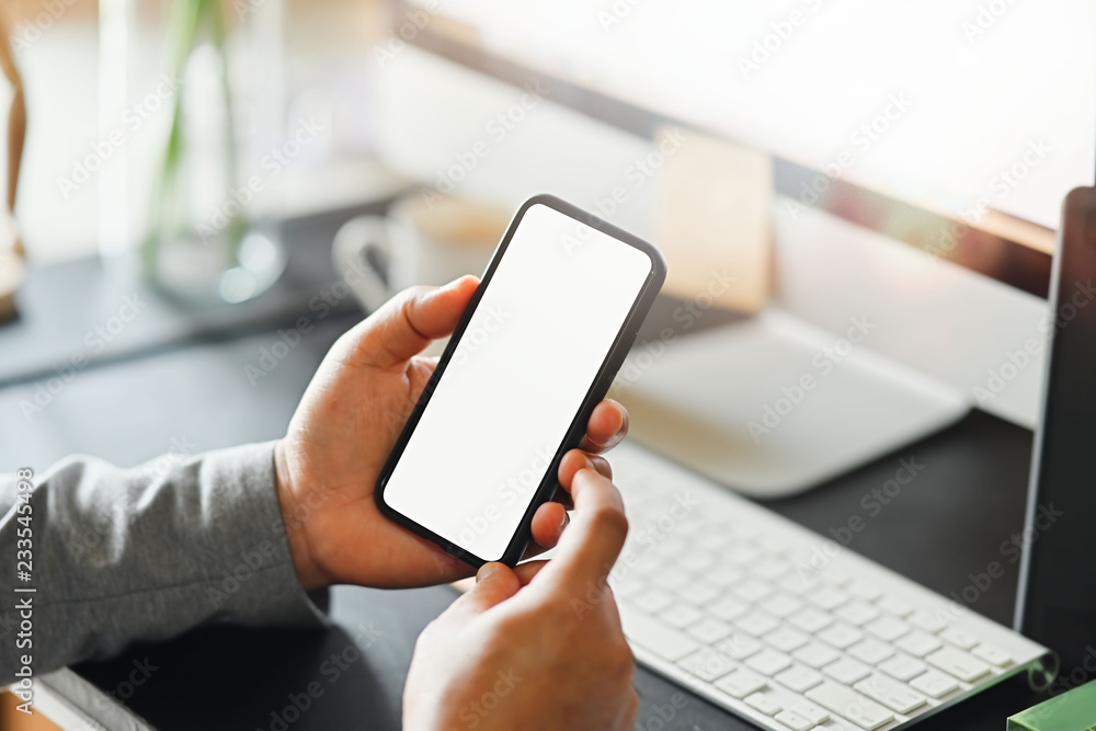 Cropped shot of man using blank screen mobile smart phone on workspace. Cropped shot of man using blank screen mobile smart phone on workspace.