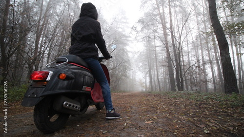 girl on a scooter in a misty forest