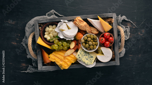 A set of cheese in a wooden box. Parmesan, Mamasam, Mozzarella, Brie, Feta. Top view. On a wooden background. Free space for your text.