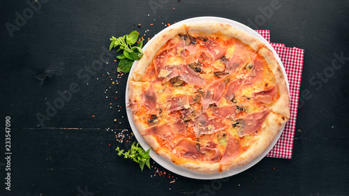 Tasty pizza with prosciutto, parmesan cheese and mushrooms. On a wooden background. Top view. Free copy space.