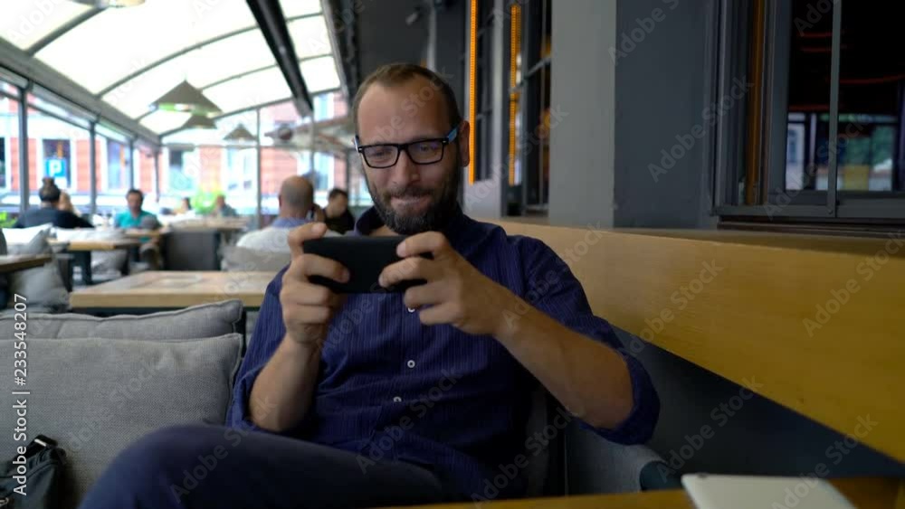 Happy, young man playing game on smartphone on sofa at home Happy, young man playing game on smartphone on sofa at home