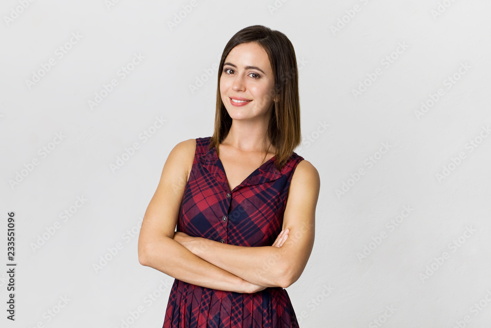Awe young brunette woman with beautiful smile and crossed arms posing against white background Awe young brunette woman with beautiful smile and crossed arms posing against white background