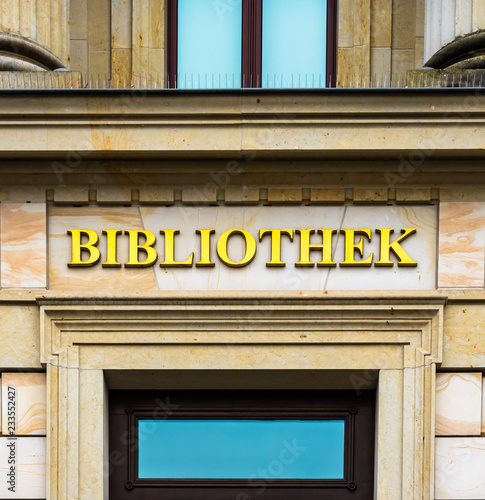 Entrance of a library in an ancient building labelled with golden letters.