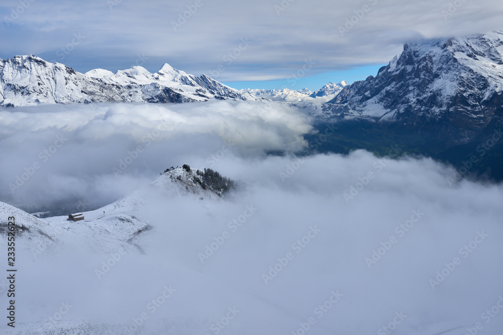 Clouds in the mountain valley with peaks above. Jungfrau region in Switzerland.