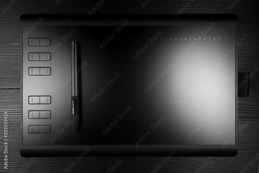 Graphic tablet with pen for illustrators and designers on black wooden background. Graphic tablet with pen for illustrators and designers on black wooden background.