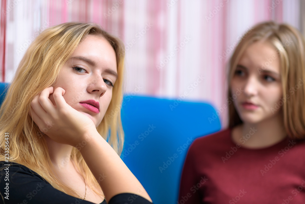 The concept a couple of beautiful young lesbian girls are talking in a room sitting on a sofa. The concept a couple of beautiful young lesbian girls are talking in a room sitting on a sofa.