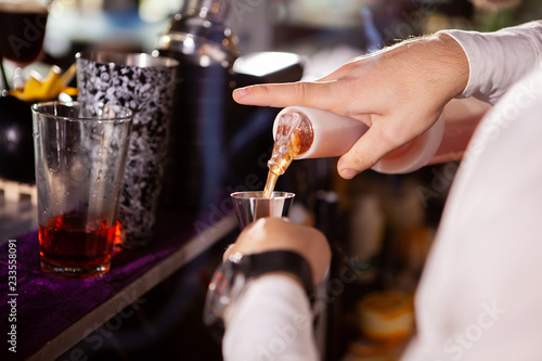 Barman in white shirt pouring drink incredient for cocktail photo