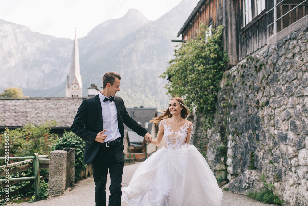 A beautiful wedding couple walks in a fairy Austrian town, Hallstatt. A beautiful wedding couple walks in a fairy Austrian town, Hallstatt.