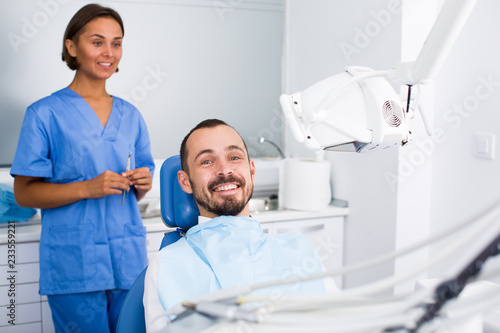 Guy is sitting satisfied after treatment in dental office