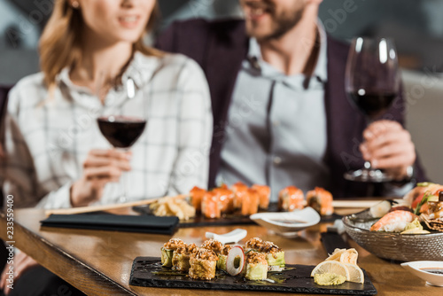 Partial view of couple eating sushi and drinking wine while having date in restaurant