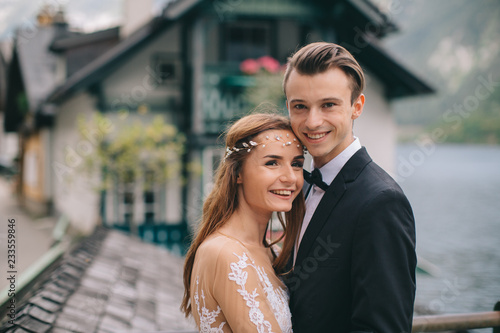 A beautiful wedding couple walks on the lake and mountains background in a fairy Austrian town, Hallstatt. © anatoliycherkas