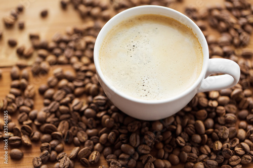 hot drinks concept - close up coffee cup and roasted beans on wooden table