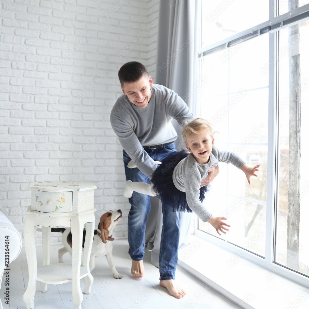 Happy father playing with his little daughter in a bright room