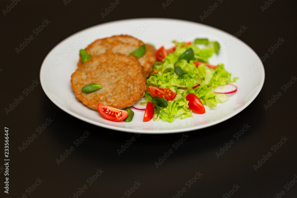 Potato pancakes with fresh mix of salad on a plate close-up. Potato pancakes with fresh mix of salad on a plate close-up.