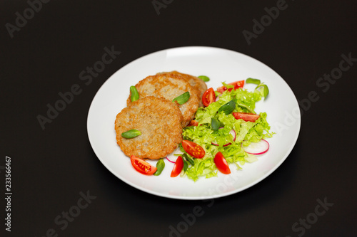 Potato pancakes with fresh mix of salad on a plate close-up.
