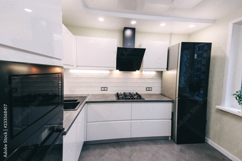 interior of a modern compact white kitchen with gas stove, oven, refrigerator. built-in furniture household appliances. interior of a modern compact white kitchen with gas stove, oven, refrigerator. built-in furniture household appliances.
