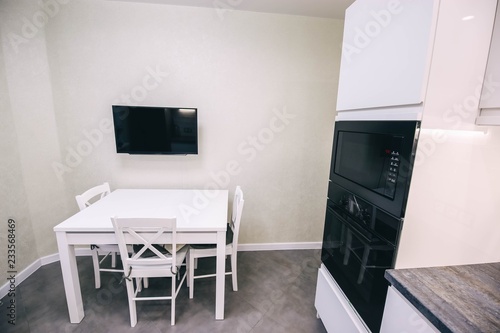  modern white kitchen interior, table, TV armchairs.