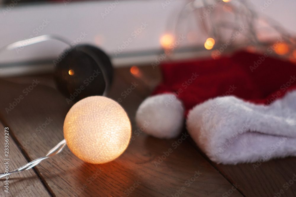 Santa Claus hat and garland lie on a wooden cover Santa Claus hat and garland lie on a wooden cover