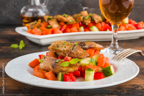 Tilapia fish fillet marinated in ginger and garlic sauce and roasted with olive oil. Fresh vegetable salad and white fish on white plate