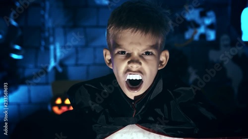Young boy in a vampire costume for Halloween showing his scary face and teeth to camera