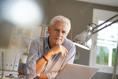 Mature man working in office, looking at camera