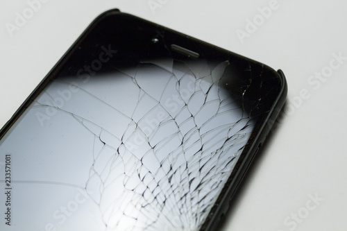 Accidentally cracked, damaged smartphone LCD screen on white background