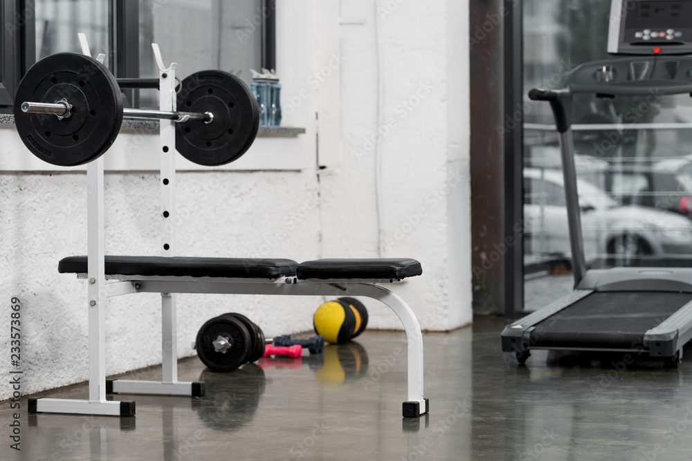 treadmill, barbell and weights in modern gym