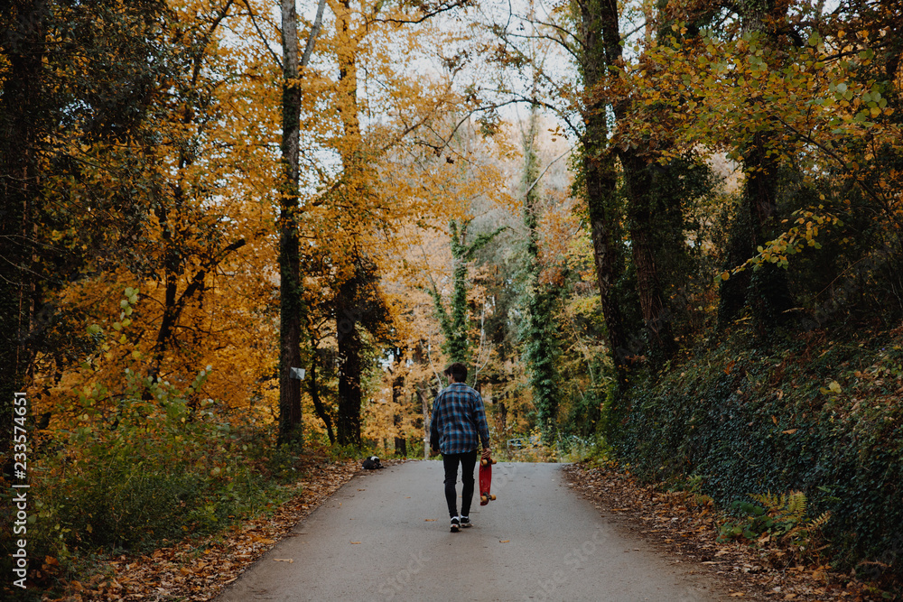 Man walking in the road in the autumn forest of Canada Man walking in the road in the autumn forest of Canada