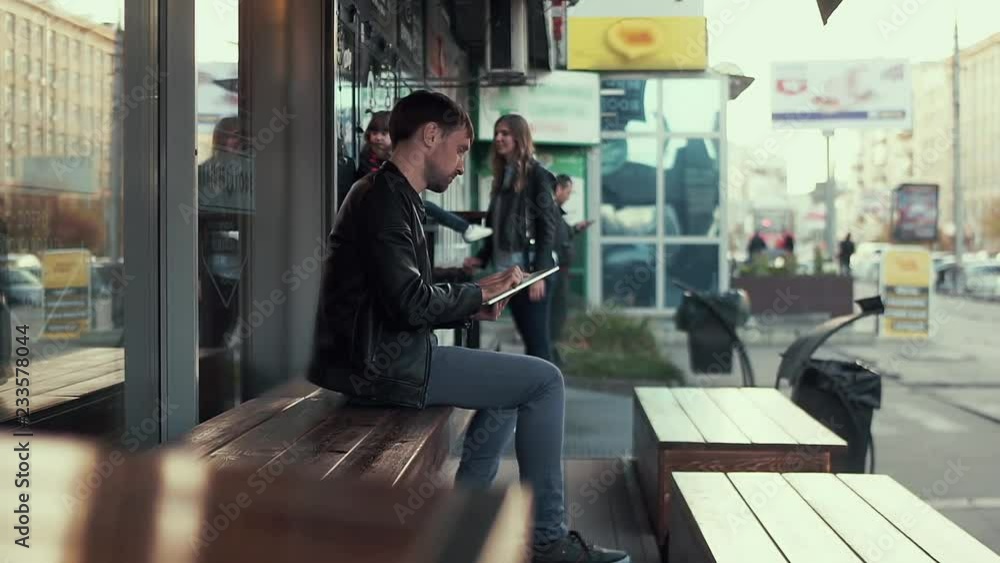 Dad works in the tablet on the street near the building, and mom and daughter play waiting for dad. Dad works in the tablet on the street near the building, and mom and daughter play waiting for dad.
