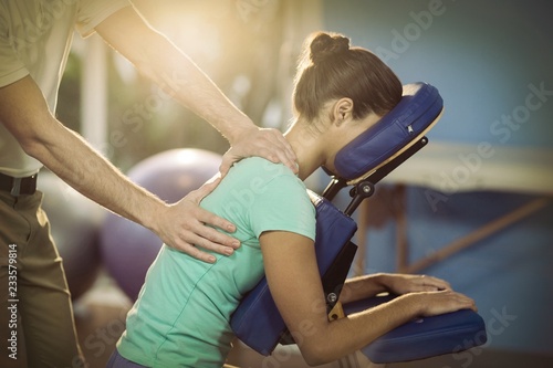 Physiotherapist giving back massage to a female patient photo