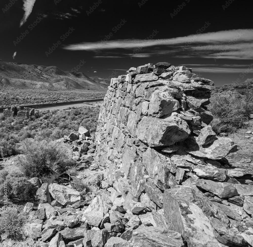 Ruined stone wall near highway in black and white
