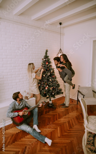 Couples hanging christmas decorations on the tree © BGStock72