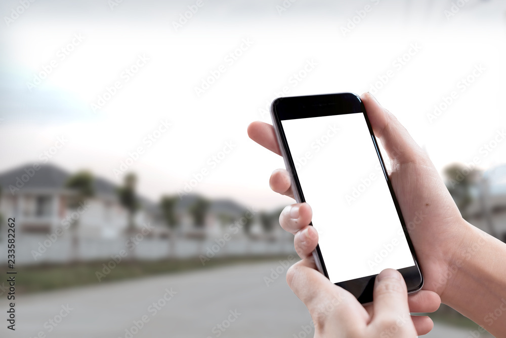 Smartphone blank screen in woman hands over blurred background at urban street.